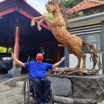 Ketut Sukaji, penyandang disabilitas warga Padangsambian Kelod berfoto di depan Patung Kuda hasil karya seninya. Foto: Lintasnusanews.com/Ist